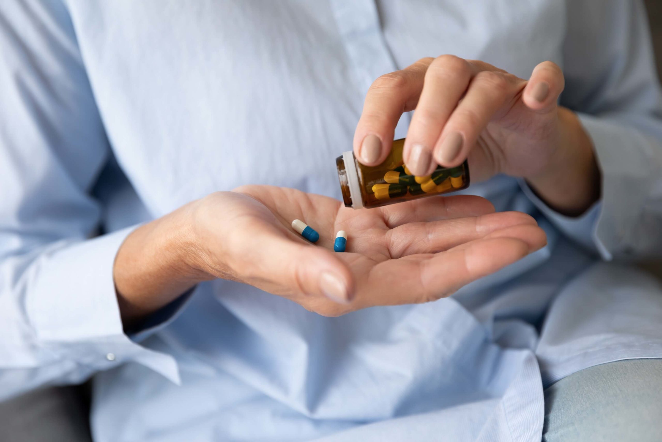 Person tipping a capsule of pills into their hand